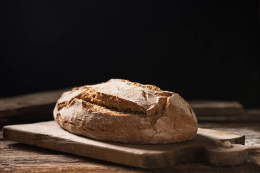 Koyu arka plan üzerinde ahşap masa üzerinde taze pişmiş ekmek