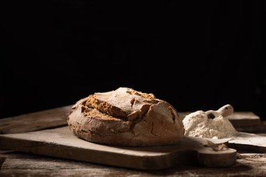 Koyu arka plan üzerinde ahşap masa üzerinde taze pişmiş ekmek