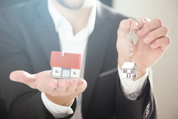 Агент по недвижимости с моделью дома и ключом — стоковое фото
