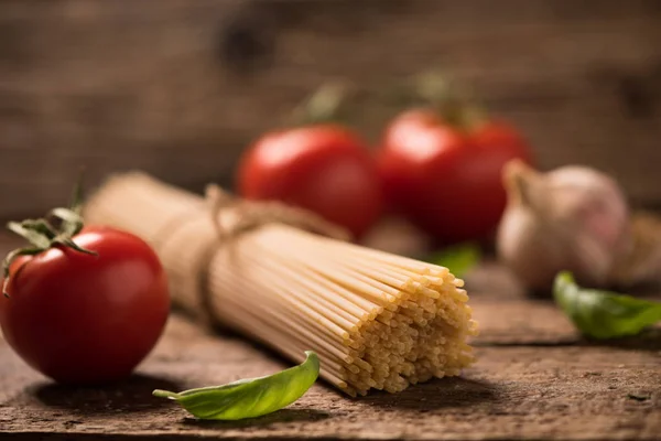 Spaghetti and tomatoes with herbs on an old and vintage wooden table