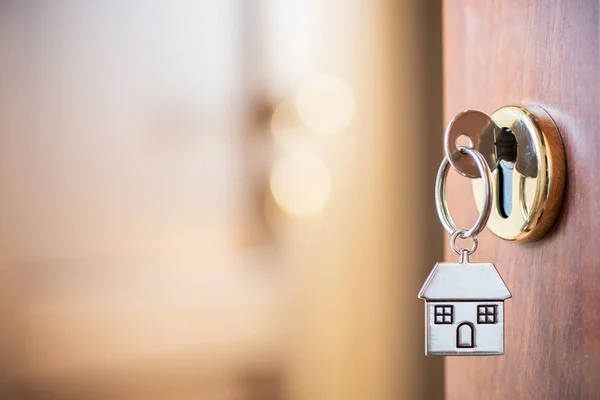 Llave de casa con llavero de casa en la cerradura de la puerta —  Fotos de Stock