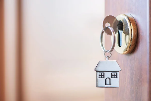 Home clé avec porte-clés maison dans le trou de serrure de la porte — Photo