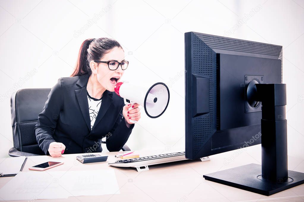 Businesswoman yelling through a megaphone sitting in the office