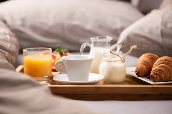 Континентальный завтрак. Поднос для завтрака на кровати с кофе, апельсин — стоковое фото