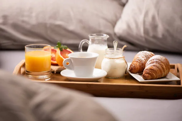 Continental πρωινό. Δίσκος πρωινού στο κρεβάτι με καφέ, πορτοκαλί — Φωτογραφία Αρχείου