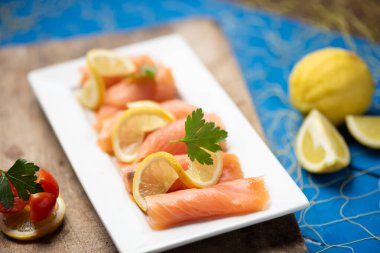 Tütsülenmiş somonu bir tabak ve mavi bir masaya yakın. 