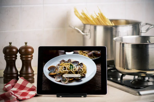 Food recipes tablet computer on rustic wooden table. Pasta Spaghetti with Clams
