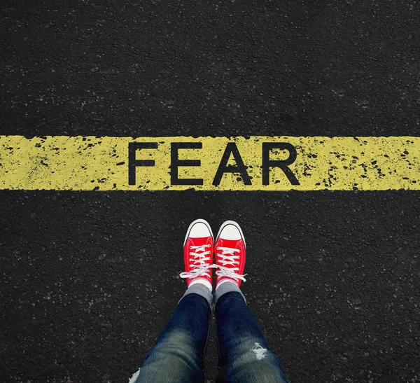 Jovem em pé na frente do sinal de medo escrito em uma faixa amarela — Fotografia de Stock