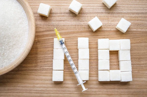 Diabetes. jeringa de insulina y ninguna palabra de los cubos de azúcar sobre fondo de madera — Foto de Stock