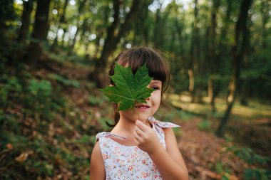 Kız ormanda bir yaprak onun elinde tutan ayakta. gizli b