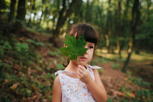 Fille debout dans les bois tenant une feuille dans ses mains. caché b — Photo