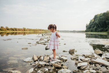 küçük bir kız taş nehrin yanında ayakta