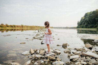 küçük bir kız taş nehrin yanında ayakta