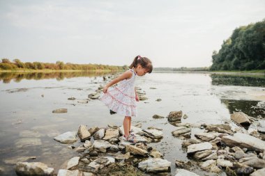 küçük bir kız taş nehrin yanında ayakta