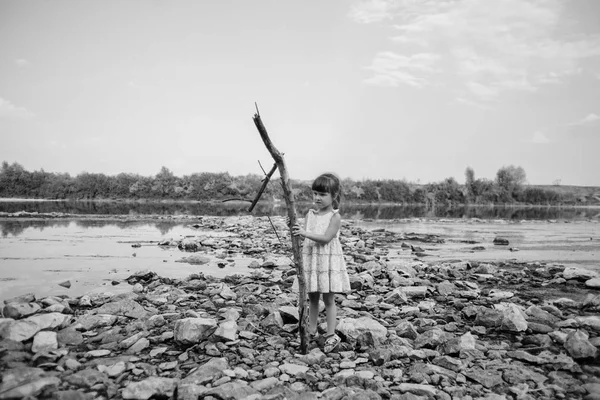 Niña sosteniendo una rama seca del río — Foto de Stock