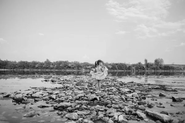 Una bambina in piedi sulle pietre vicino al fiume — Foto Stock