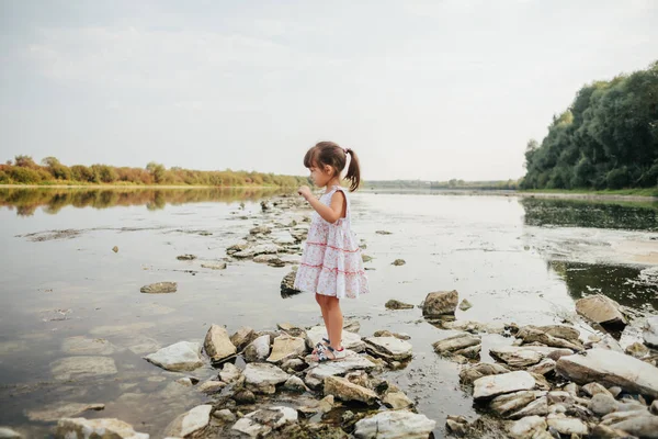 küçük bir kız taş nehrin yanında ayakta