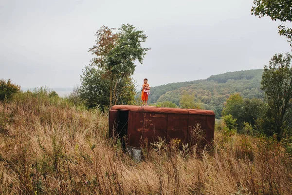 bir bebek ile küçük kız ormanda eski römork üzerinde duruyor