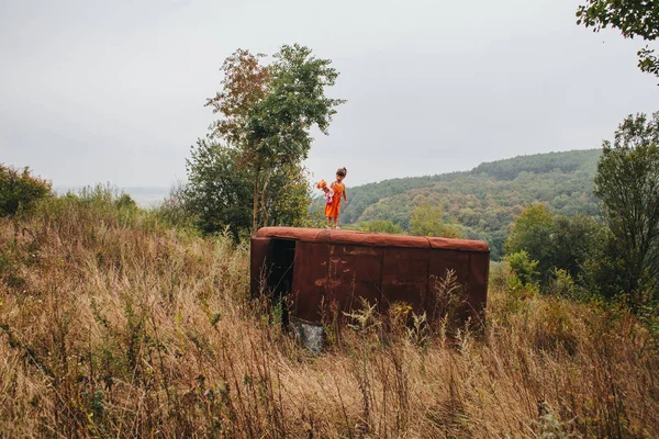 bir bebek ile küçük kız ormanda eski römork üzerinde duruyor
