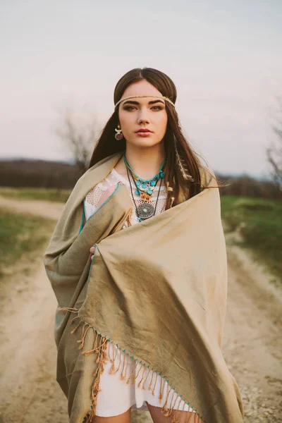 Hippi kız toprak yolda ayakta.