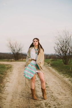 Hippi kız toprak yolda ayakta.