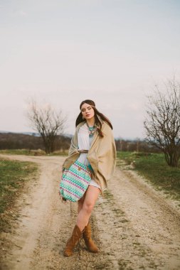 Hippi kız toprak yolda ayakta.