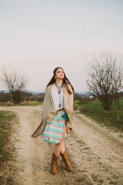 Hippi kız toprak yolda ayakta.