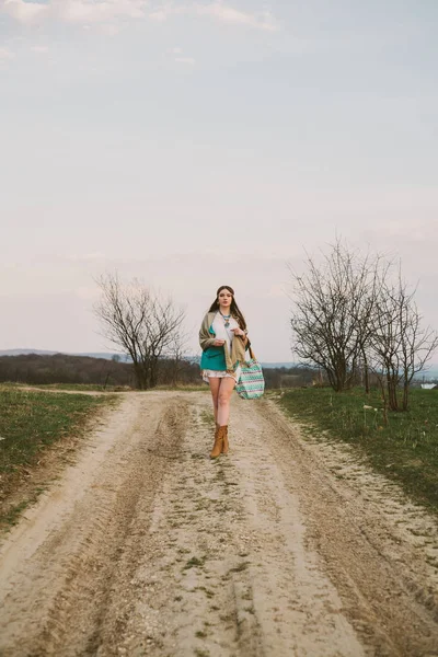 Хипстерская девушка стоит на грунтовой дороге — стоковое фото