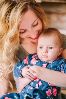 Anne kızı onun kollarında tutar..