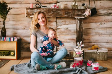 Anne kızı onun kollarında tutar..