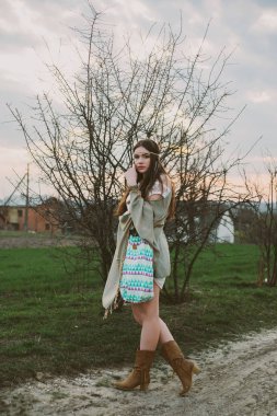 Hippi kız toprak yolda ayakta.