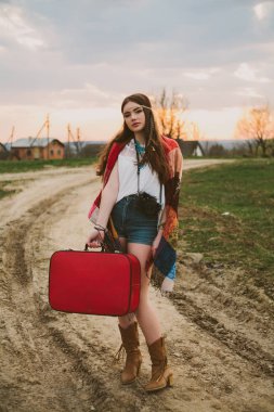 Hippi kız toprak yolda ayakta.