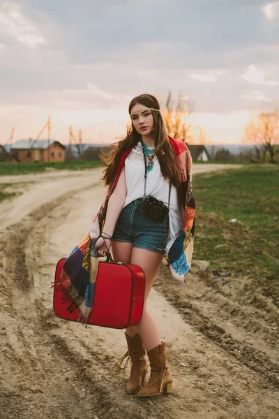 Hippi kız toprak yolda ayakta.