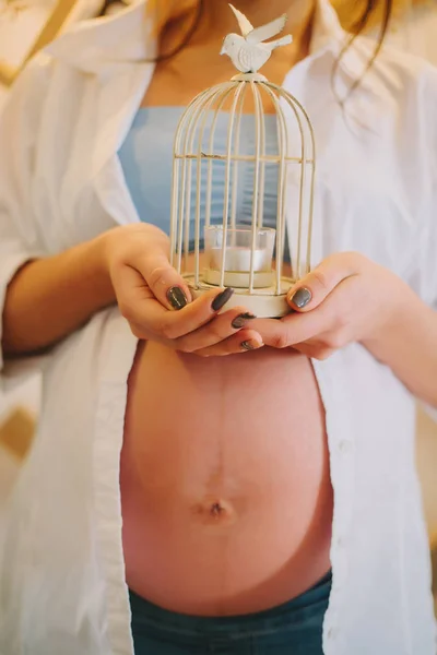 A pregnant girl holds a candlestick in her hands.bird — Stock Photo, Image