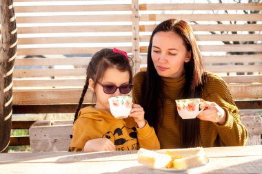 Anne ve kızı çardakta çay içerler. Güneş ışığı