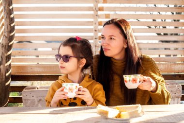 Anne ve kızı çardakta çay içerler. Güneş ışığı