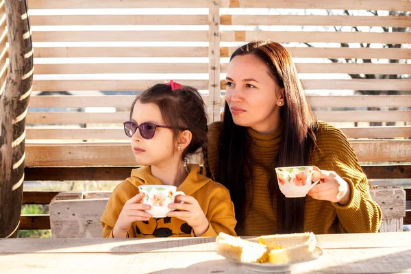 Anne ve kızı çardakta çay içerler. Güneş ışığı