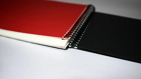 Красный ноутбук с черной обложкой на белом фоне — стоковое фото