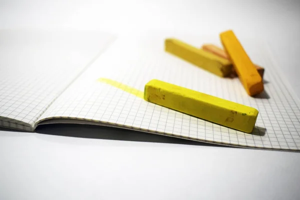 yellow and orange pastel crayons on a white notebook