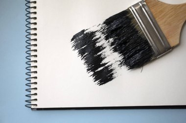 Açık defter mavi bir arka plan üzerinde fırça ile. Siyah boya