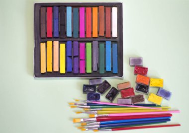 Çok renkli fırçalar, suluboya ve pastel yeşil bir arka plan üzerinde
