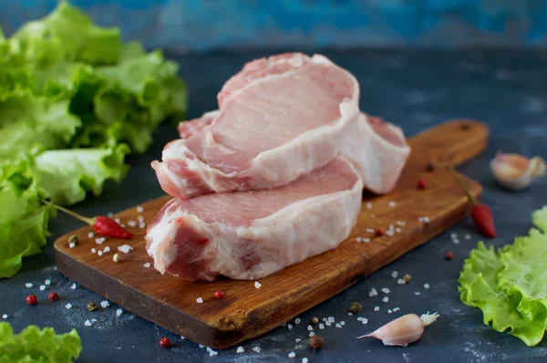 Çiğ et parçaları üzerinde ahşap bir masa, tuz, biber.