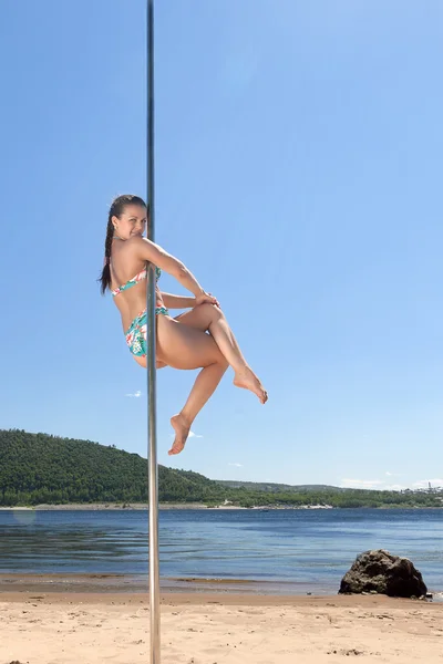 Dancer on pole on background of river beach — Stock Photo, Image