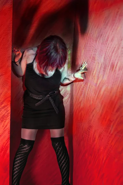 Menina em vestido preto no fundo da parede vermelha — Fotografia de Stock