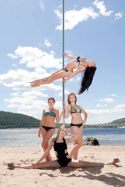 Группа девушек в купальниках на танцах на шесте — стоковое фото