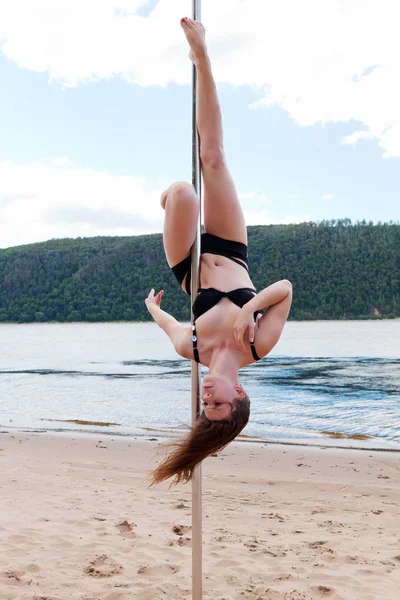 acrobatic performance brunette in swimsuit on pole for dancing