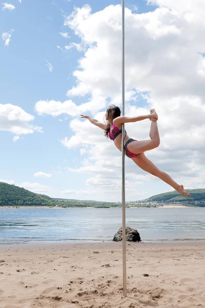Akrobatický výkon bruneta v plavkách na pól k tanci — Stock fotografie