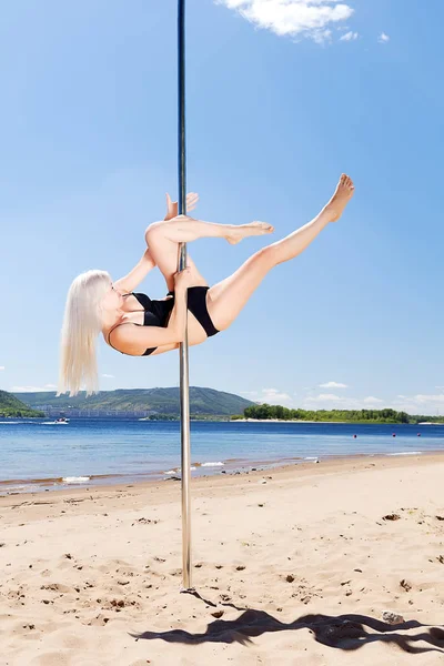 Blonde Tänzerin führt Akrobatik an Stange auf — Stockfoto