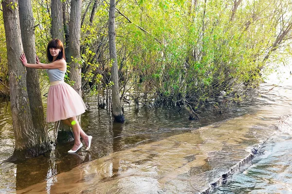 Girl in summer dress surrounded by greenery running along water — Stock Photo, Image