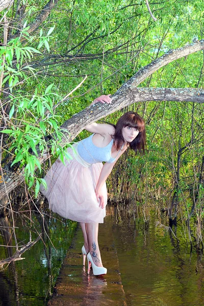 Menina em vestido de verão cercado por vegetação correndo ao longo da água — Fotografia de Stock